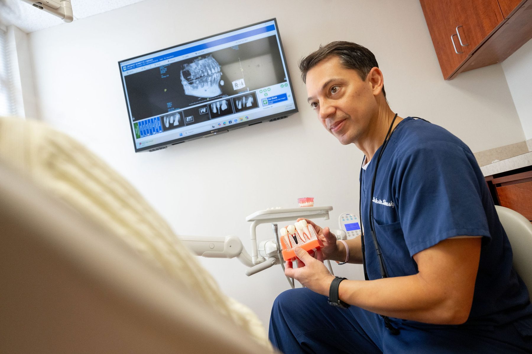 Dr. Zalewsky demonstrating dental implant model to patient