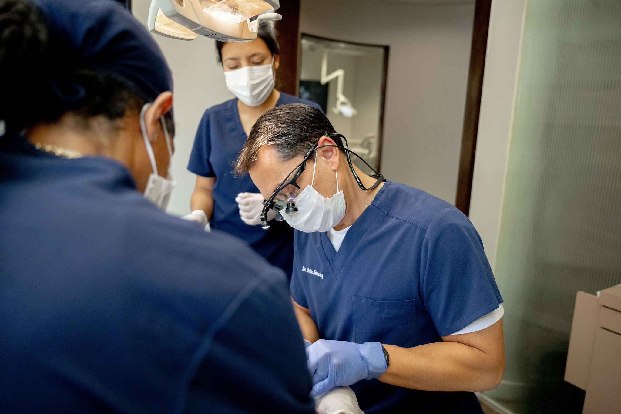 Three clinicians during a periodontal procedure
